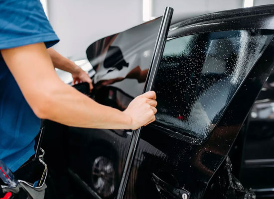 Carbon film being installed on the front side window of a sedan at Zoz Auto Detailing in Rochester, MN